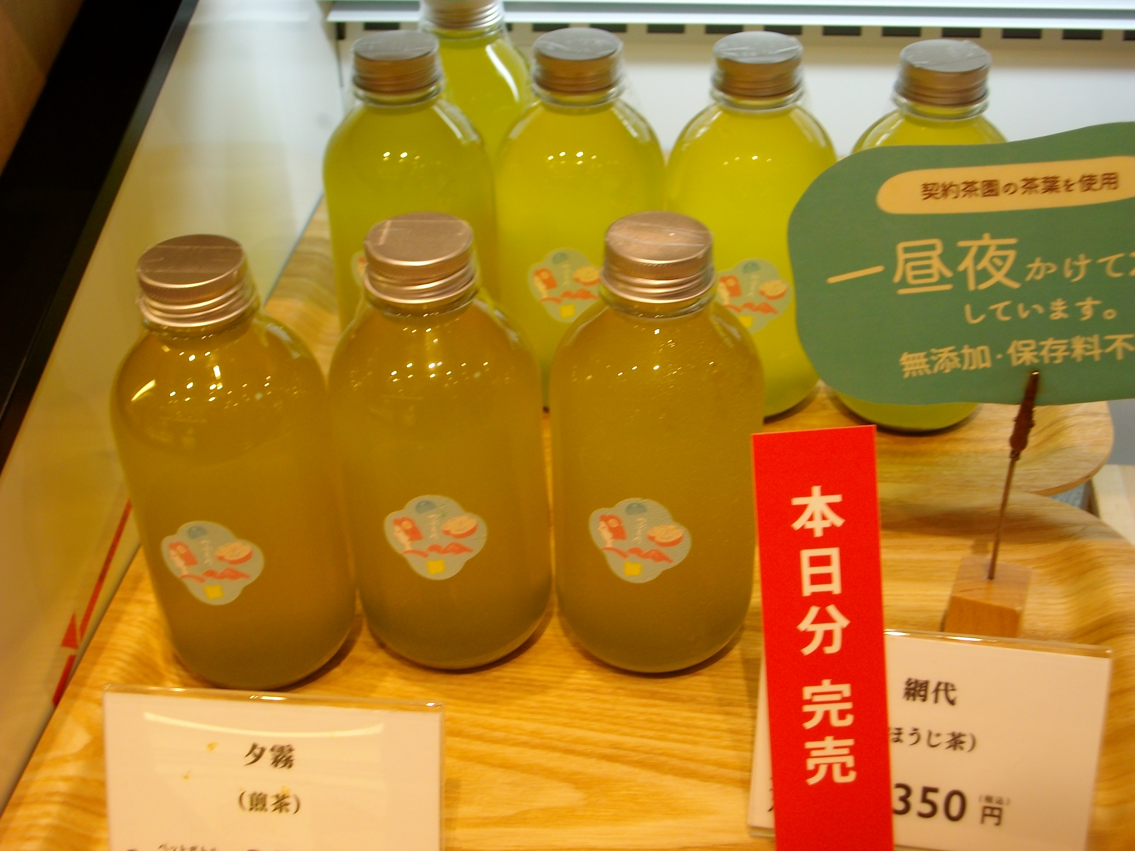 几瓶绿色玻璃瓶装绿茶饮料摆放在一起，体现瓶装茶作为现成商品的货架属性