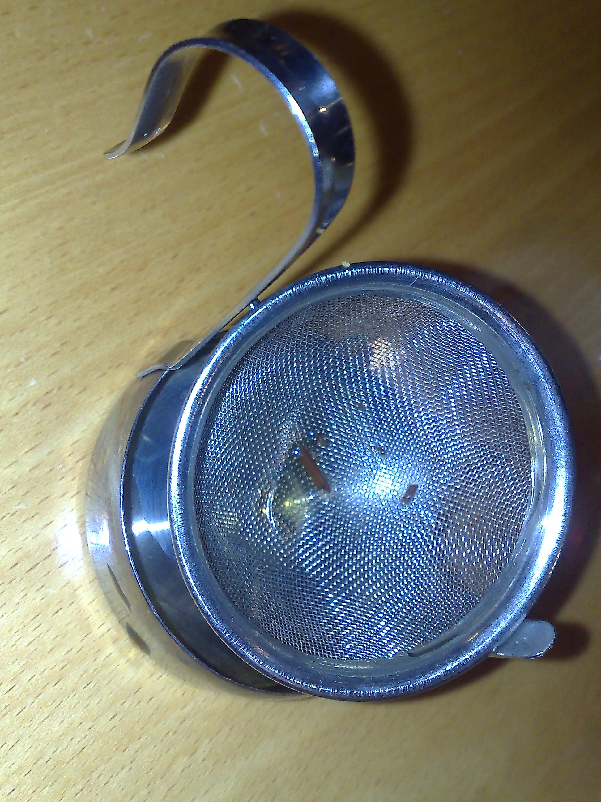 细密金属茶滤的近景，可见网面结构与把手，说明茶滤本身也是有孔径、容量和清洗成本差别的器物